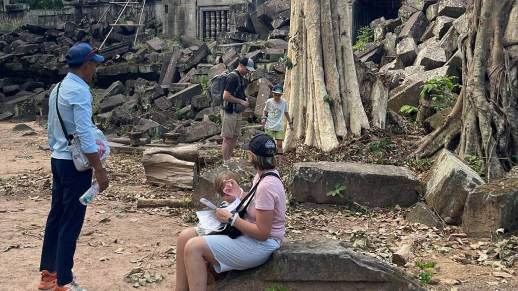 Guía local y viajeros durante una visita en un sitio de Angkor, en Camboya