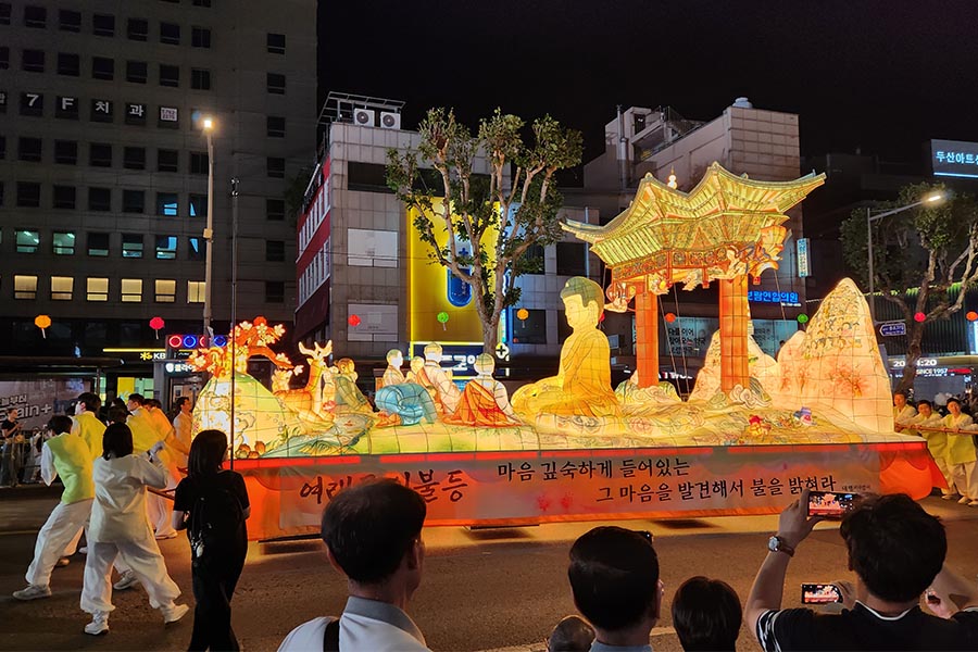Carroza budista iluminada durante el festival Yeondeunghoe en Seúl, rodeada de linternas y espectadores.