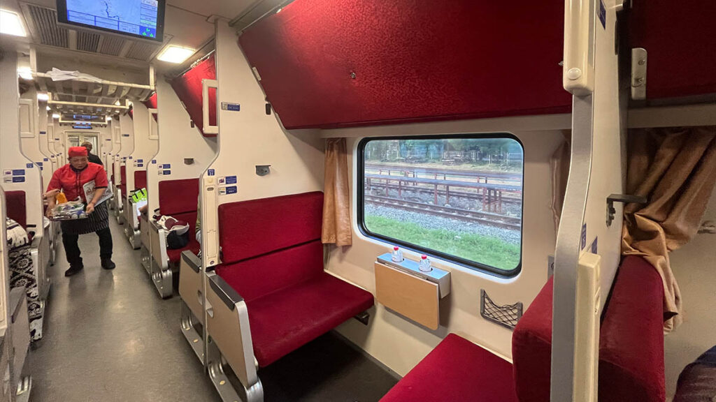 Interior de un vagón de tren nocturno en Tailandia con asientos convertibles en literas