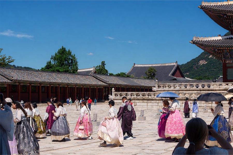 Visitantes vestidos con hanbok en el patio del palacio Gyeongbokgung de Seúl durante el verano