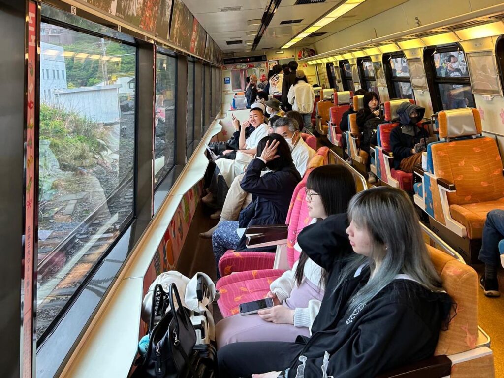 Pasajeros a bordo de un tren panorámico recorriendo la costa de la península de Izu en Japón