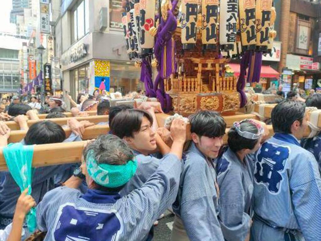 Porteadores transportando un mikoshi entre la multitud durante un matsuri en Tokio