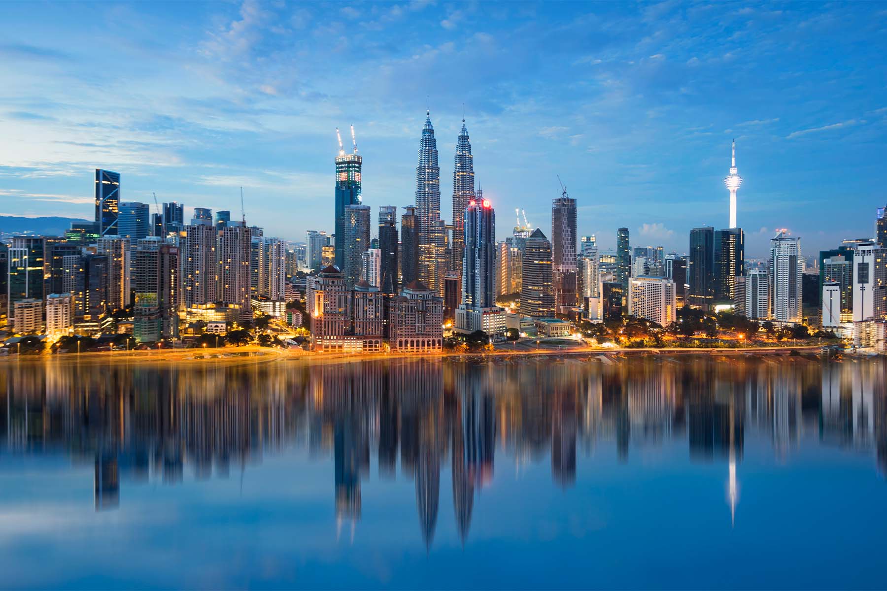 Rascacielos de Kuala Lumpur reflejados en el agua al anochecer, Malasia.