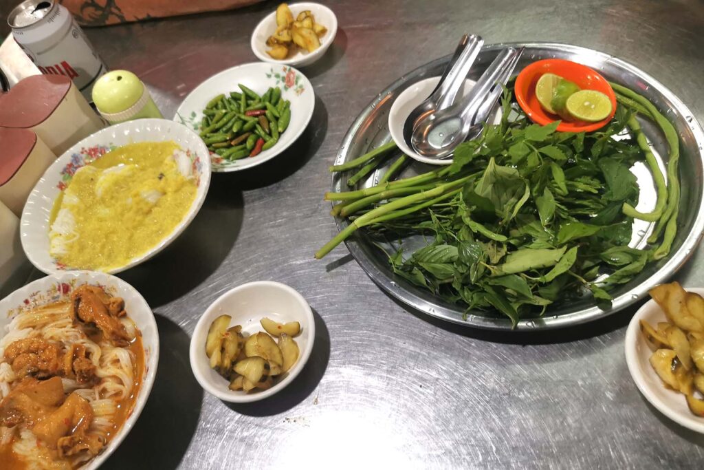 Dos cuencos de num banh chok, fideos de arroz camboyanos acompañados de hierbas frescas